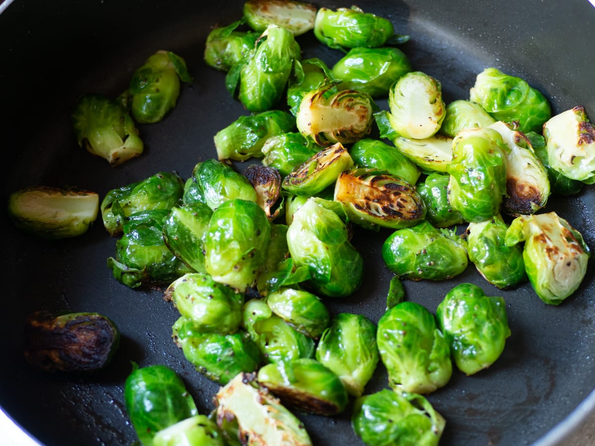 Stirred Brussels sprouts after initial cooking time showing caramelized surfaces.