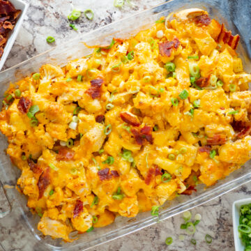 Buffalo chicken casserole in a glass dish topped with green onions and bacon.