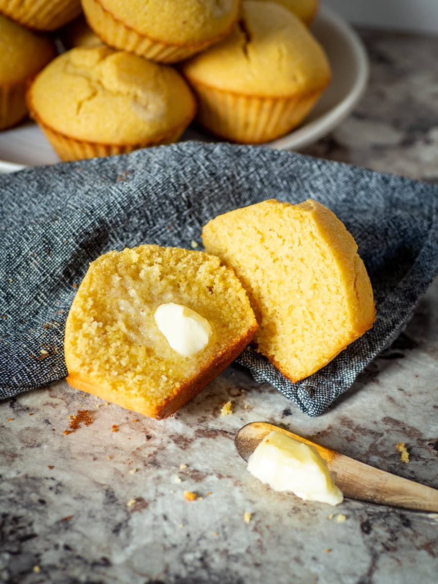 Cornbread muffin sliced in half on a napkin and topped with butter.