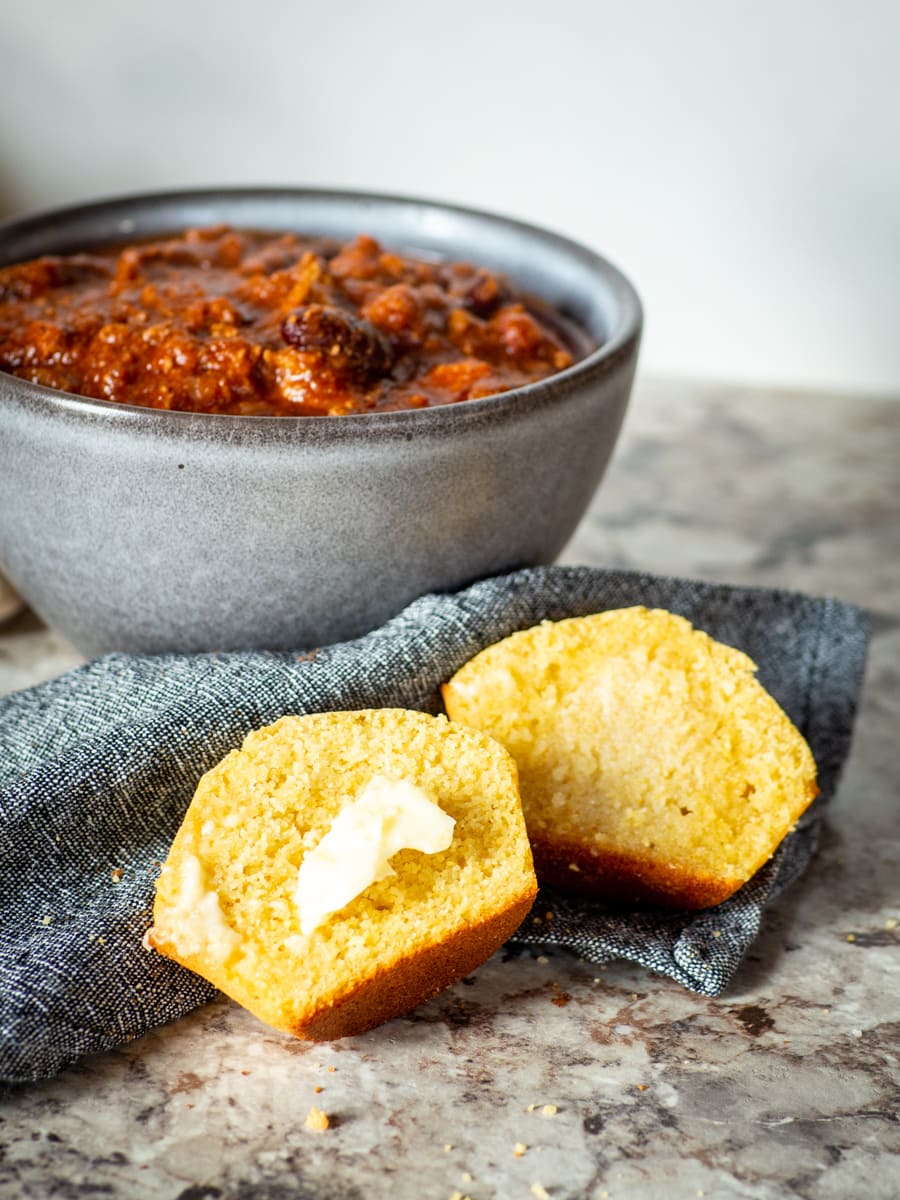 Buttered cornbread next to a bowl of chili.