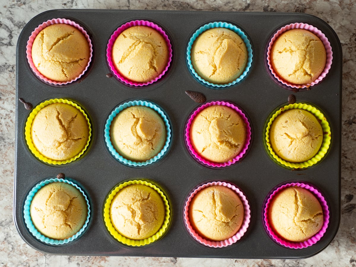 Baked oat flour cornbread muffins in a muffin tin.