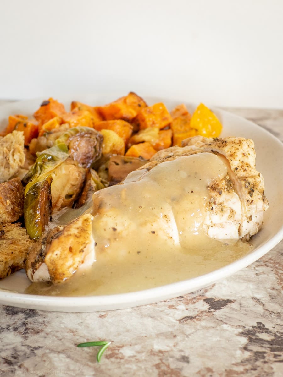 Gravy on top of a piece of roasted chicken.