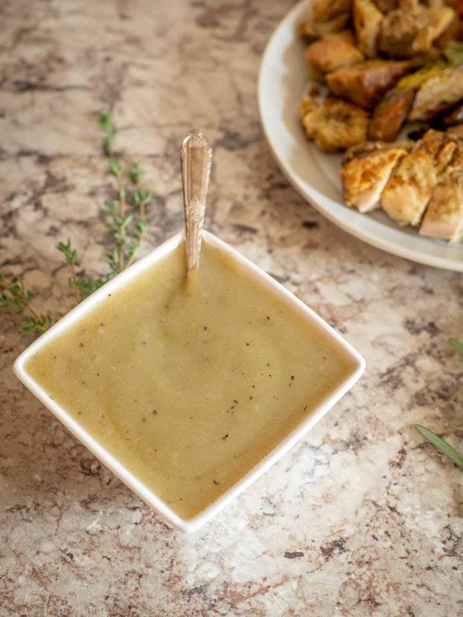 Bowl of gravy next to a dish of Thanksgiving sides.