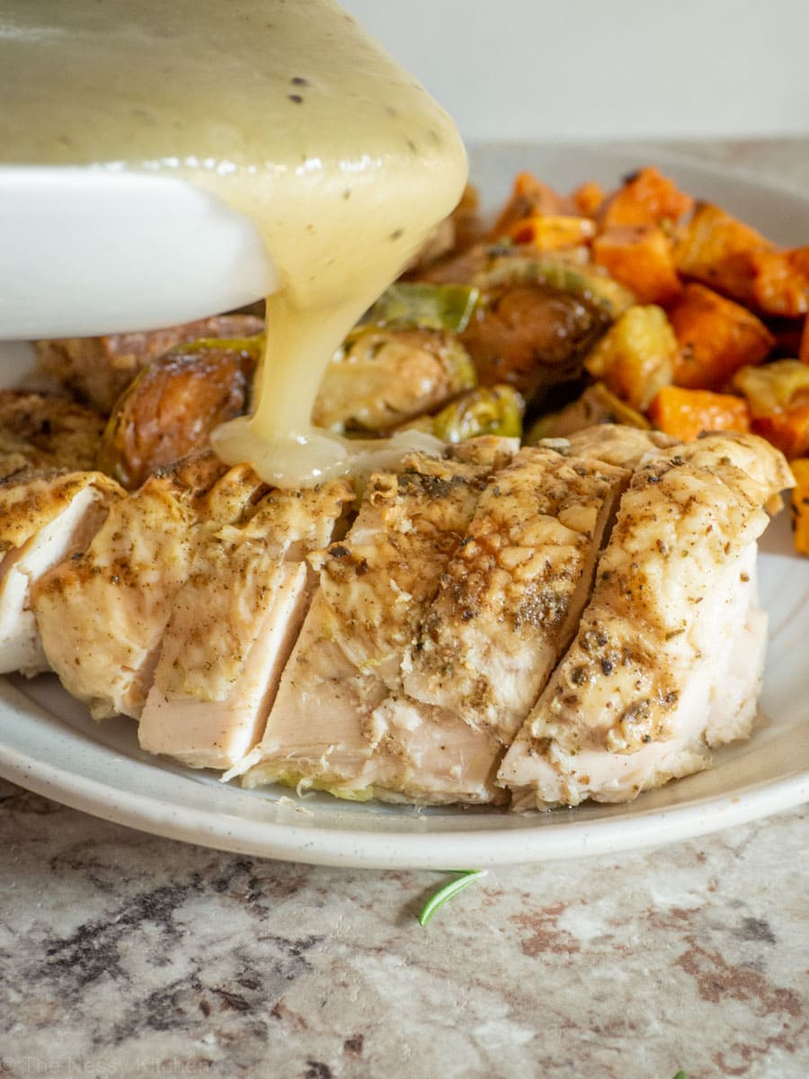 Gravy being poured over a plate of chicken dinner.