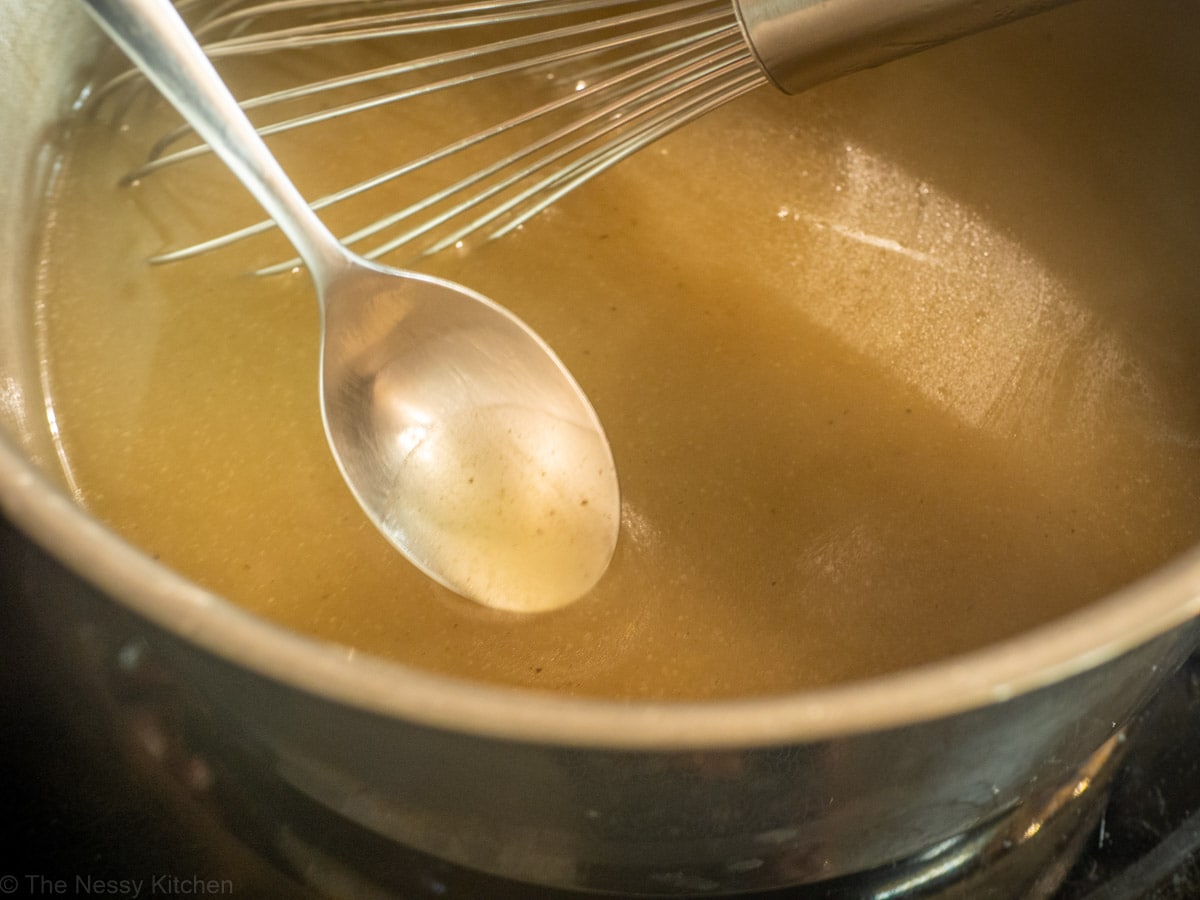 Spoon scooping a taste of gravy out of the pot prior to seasoning.