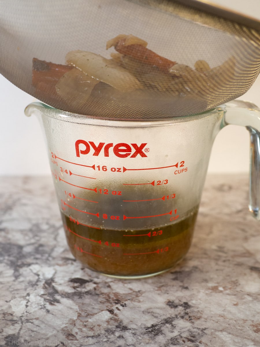 Drippings being strained into a measuring cup.