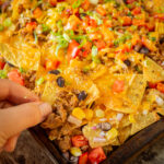 Hand grabbing a bite of ground turkey nachos.