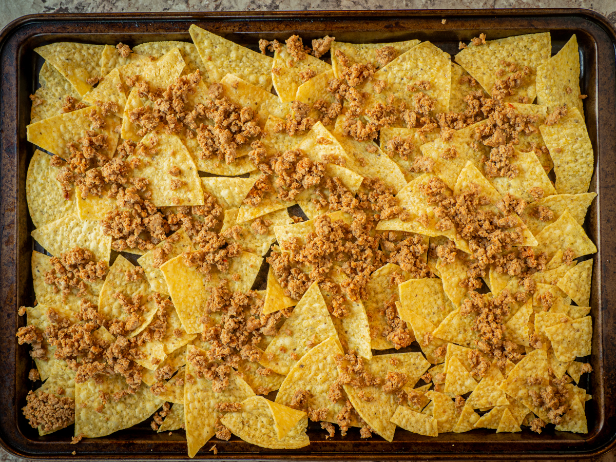 Ground turkey spread out over a layer of tortilla chips.