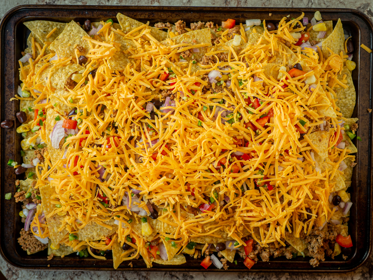 Assembled nachos on a sheet pan prior to baking.
