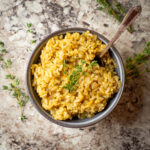 Pumpkin rice in a bowl and garnished with a sprig of thyme.