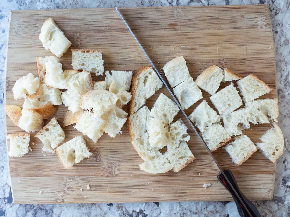 Bread sliced into cubes on a cutting board.