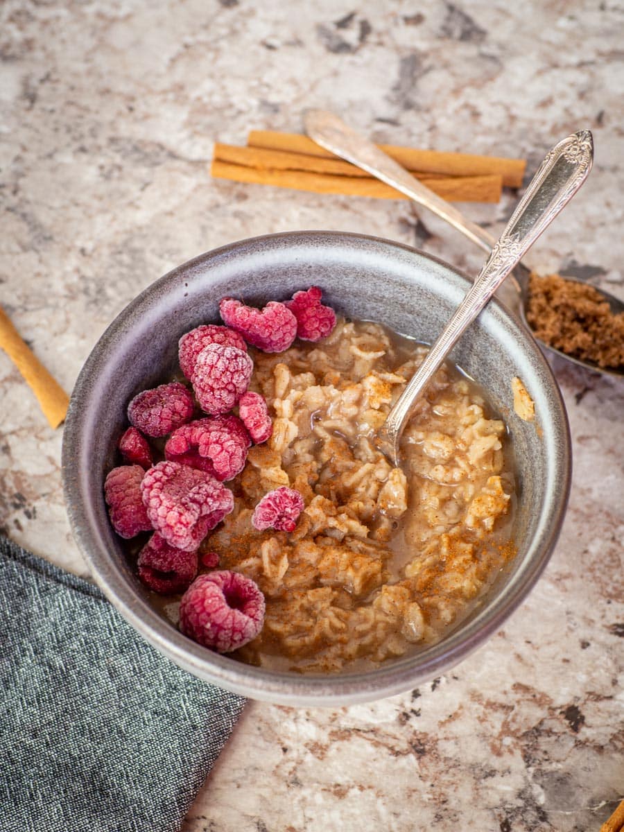 Bowl of oatmeal topped with raspberries.