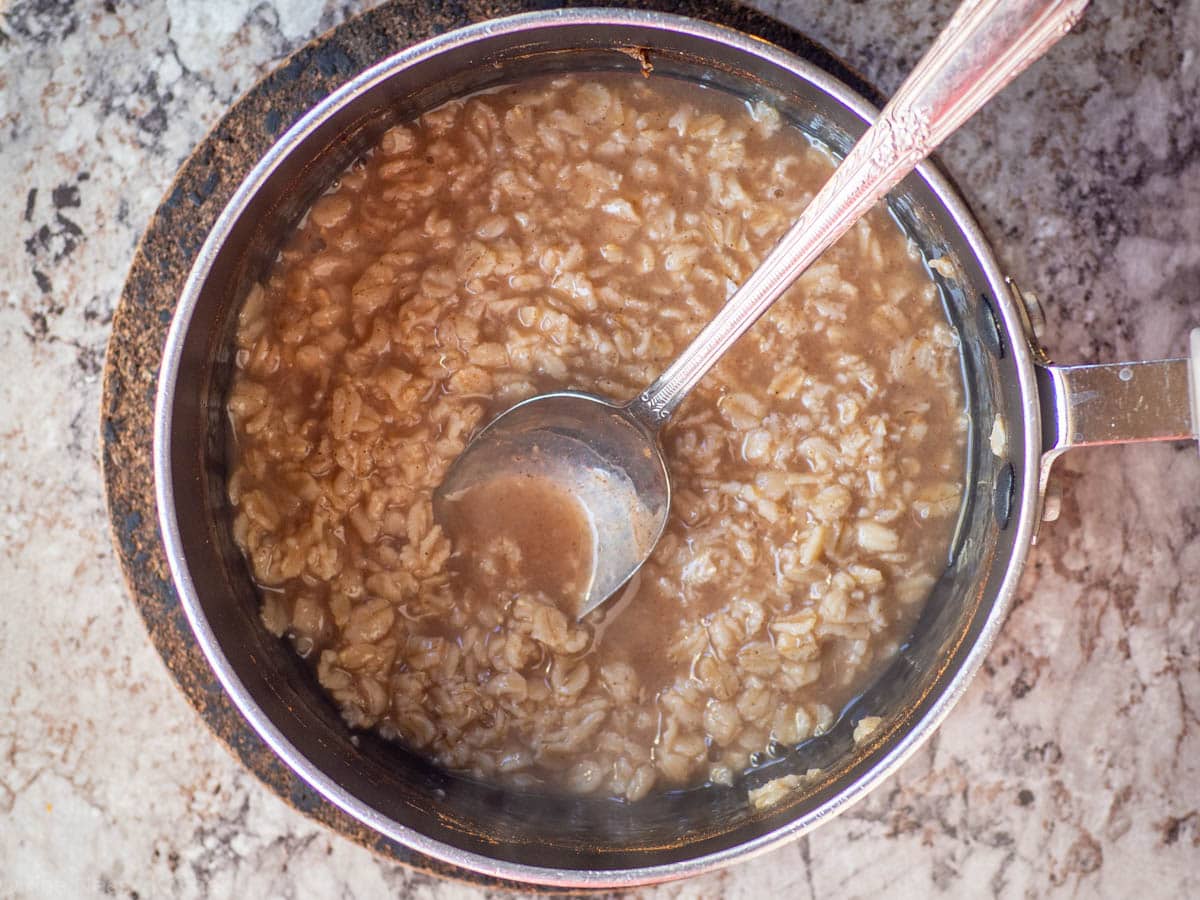 Cooked oatmeal in a pot with a spoon.