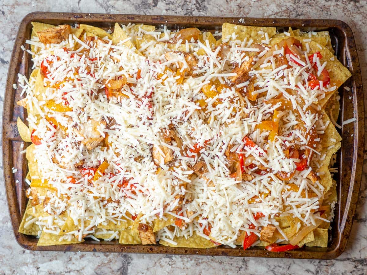 Cheese spread out over a sheet pan of nachos.