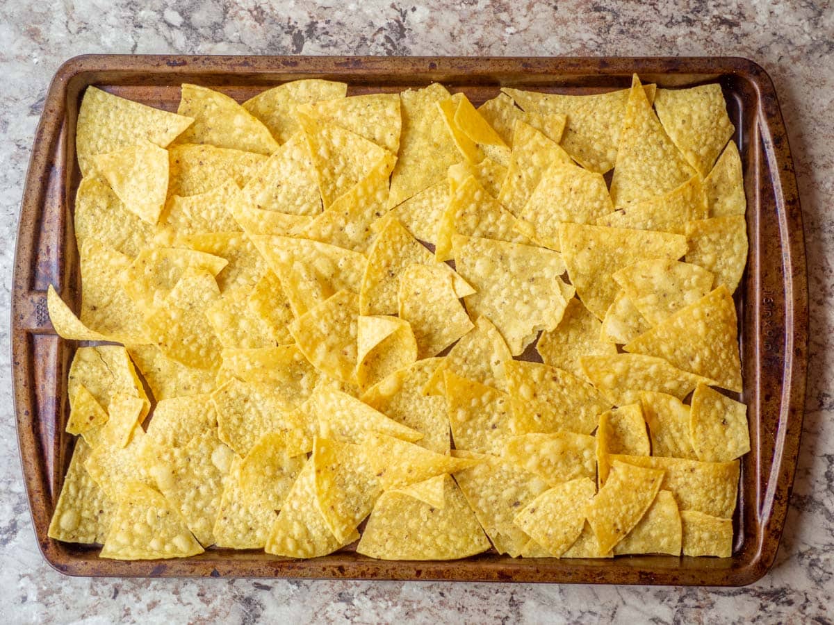 Tortilla chips spread out a baking pan.