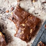 Chocolate peanut butter protein bar on a countertop with a bite taken out.