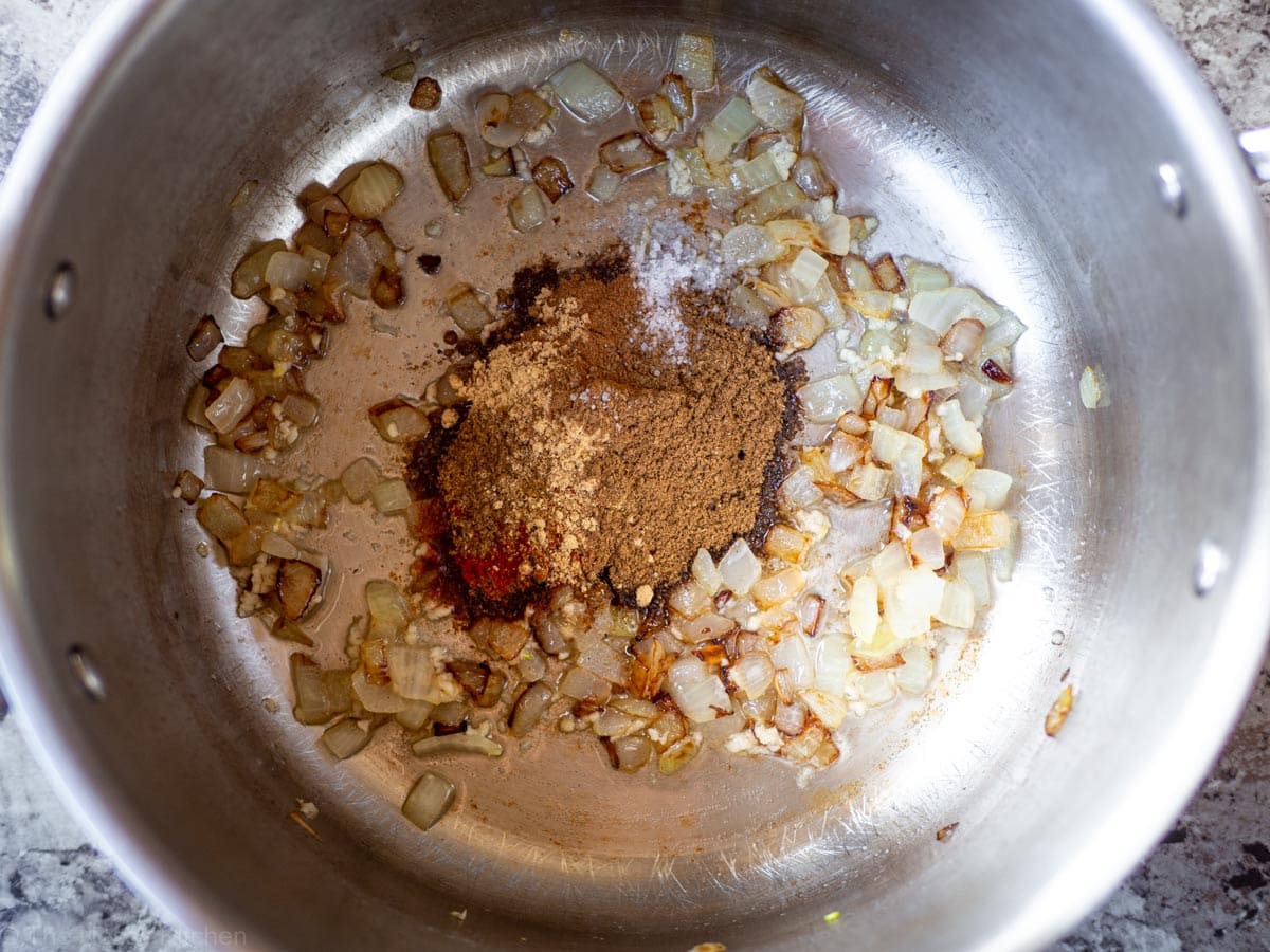 Sautéed onions and spices in the bottom of a pot.