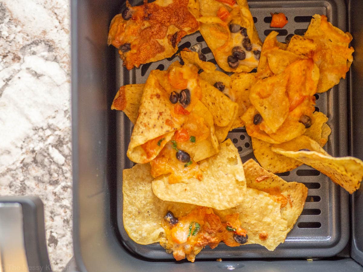 Nachos that have been reheated in the basket of an air fryer.