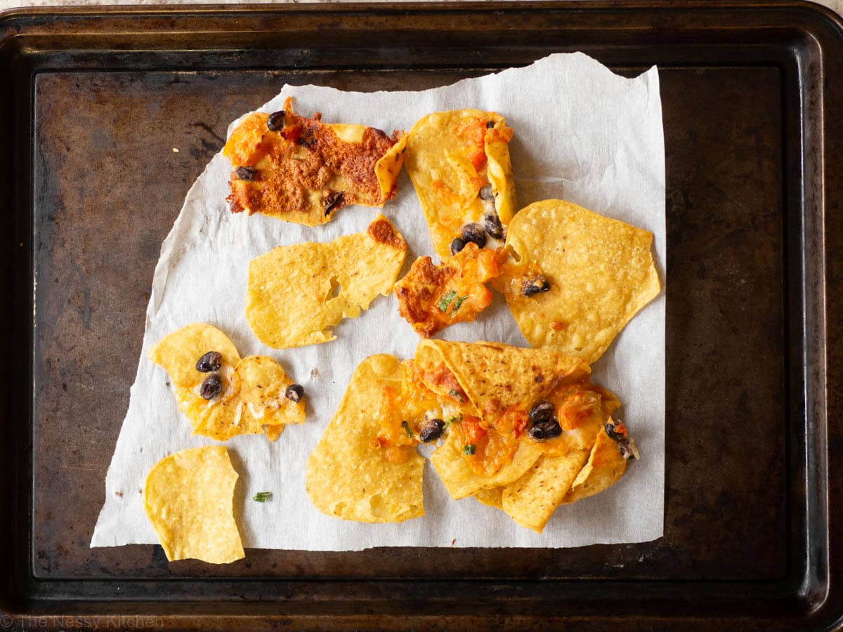 Baking sheet with leftover nachos that have been warmed in the microwave.