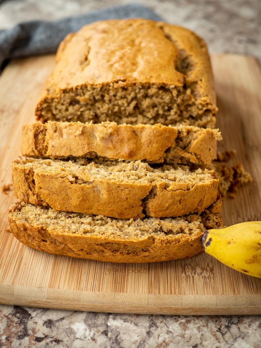 Banana bread sliced on a wooden cutting board.