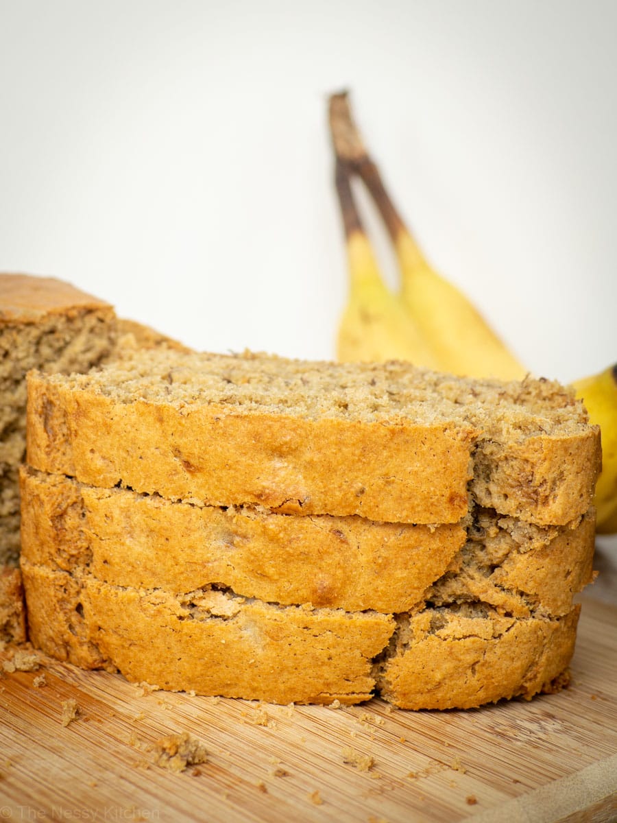 Slices of banana bread stacked on a cutting board.