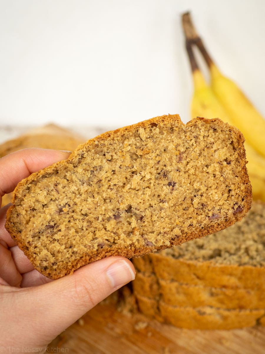 Hand holding up a slice of oat flour banana bread.