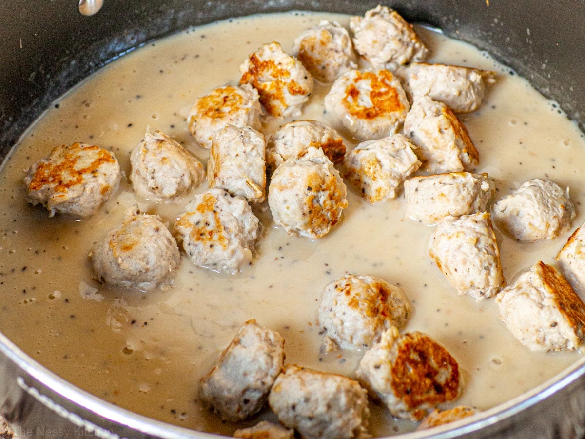 Meatballs in a skillet with creamy sauce.