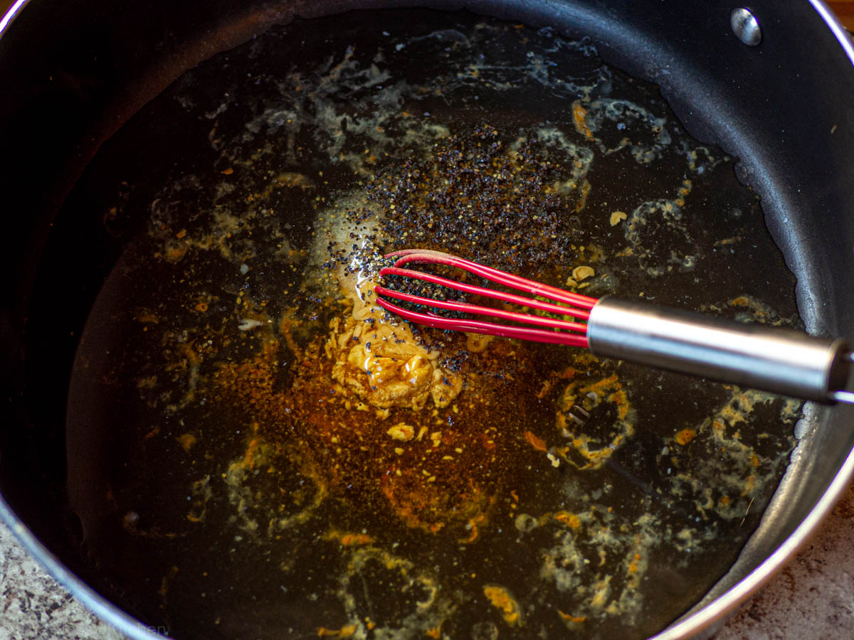 Skillet with gravy ingredients and a whisk.