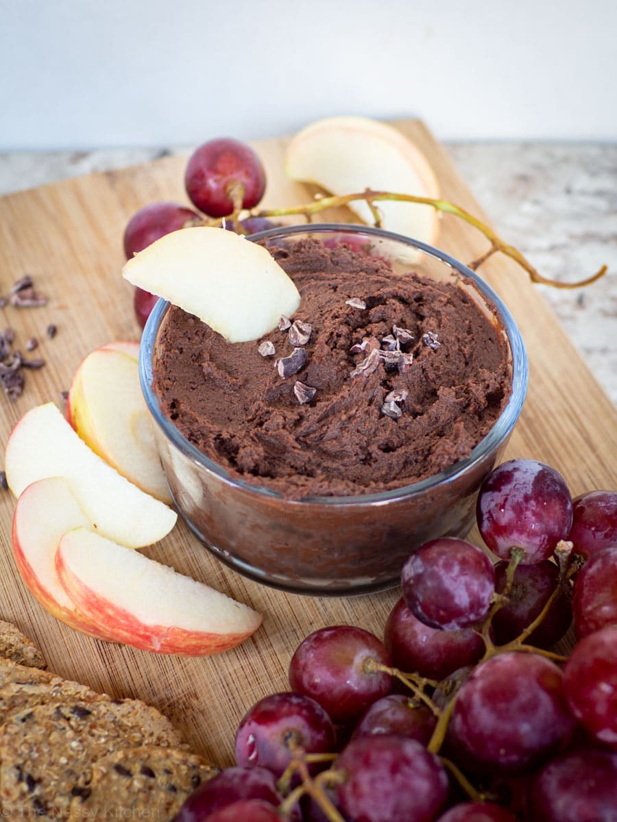Apple dipped in a bowl of chocolate hummus.