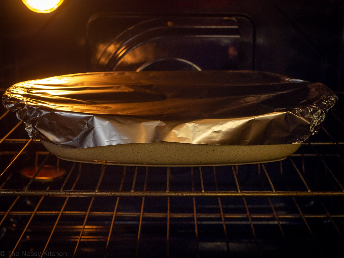 Casserole dish topped with aluminum foil in the oven.