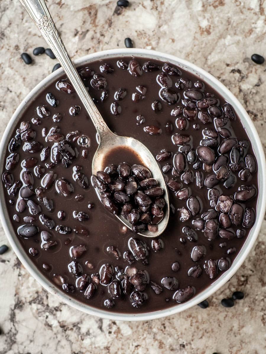 Bowl of black beans with a spoon.