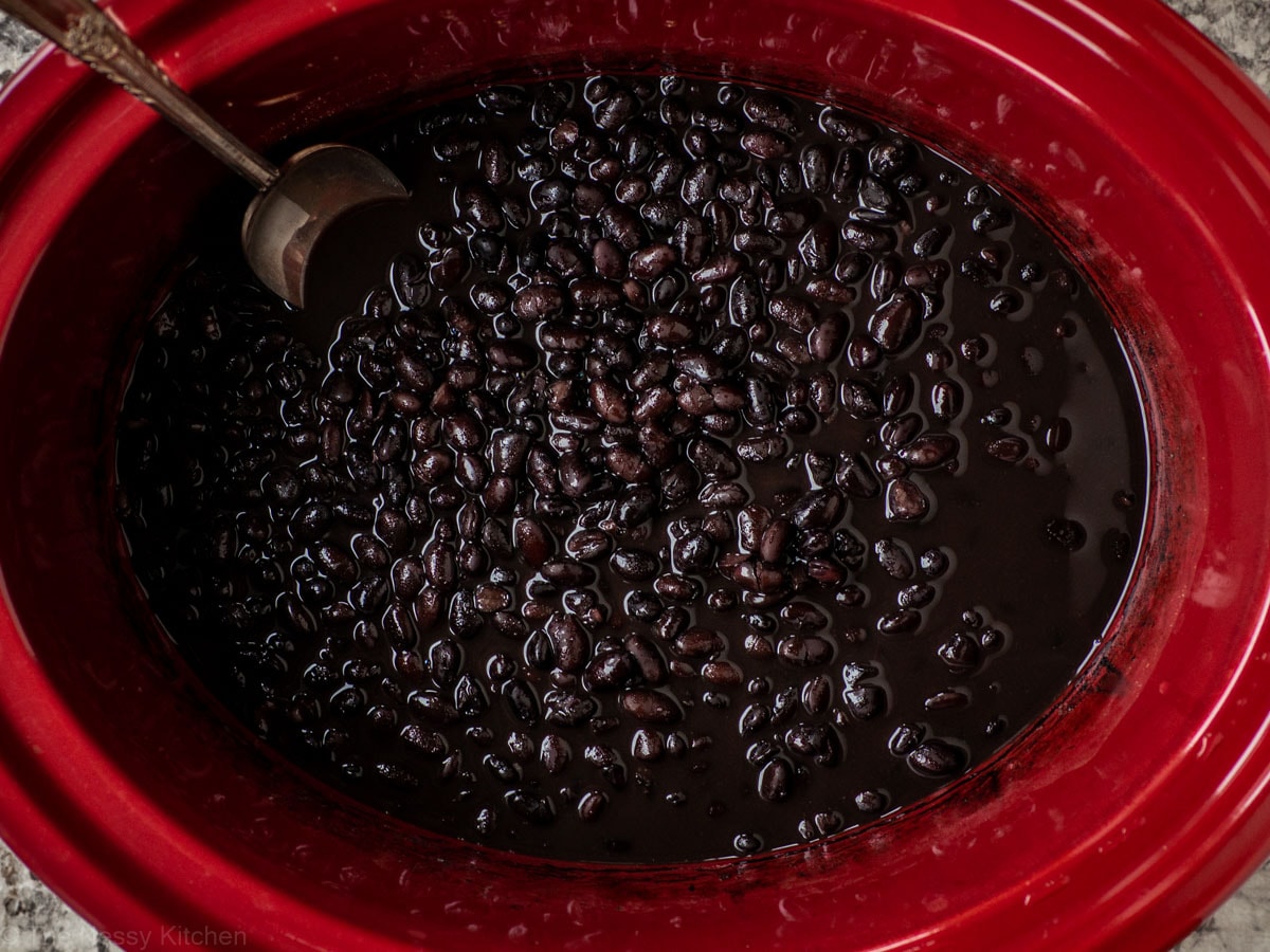 Cooked black beans in the base of a slow cooker.