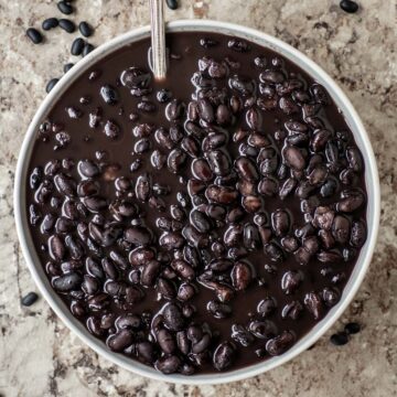 Bowl of cooked black beans with a spoon.