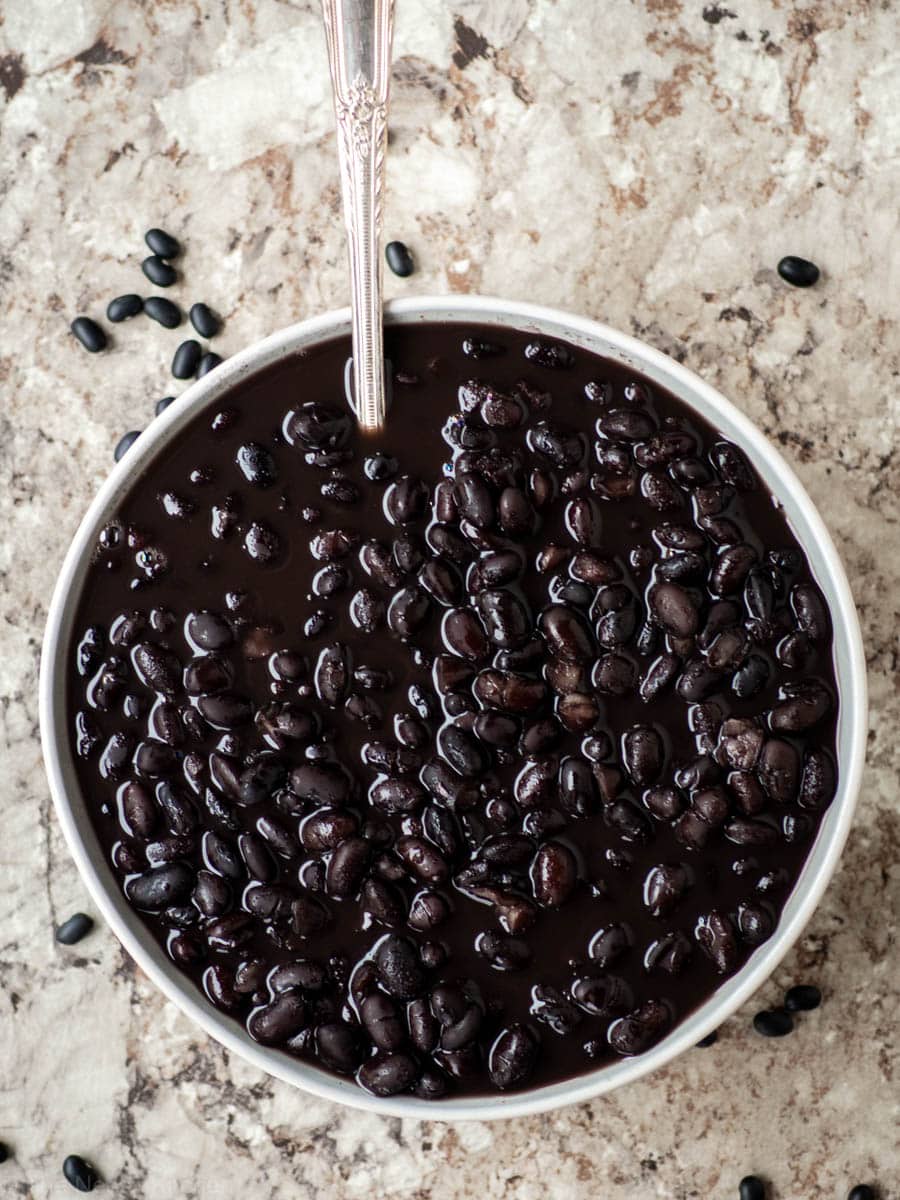 Black beans in a bowl with a spoon.
