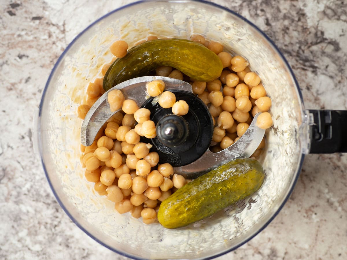 Chickpeas and pickles added to a food processor.