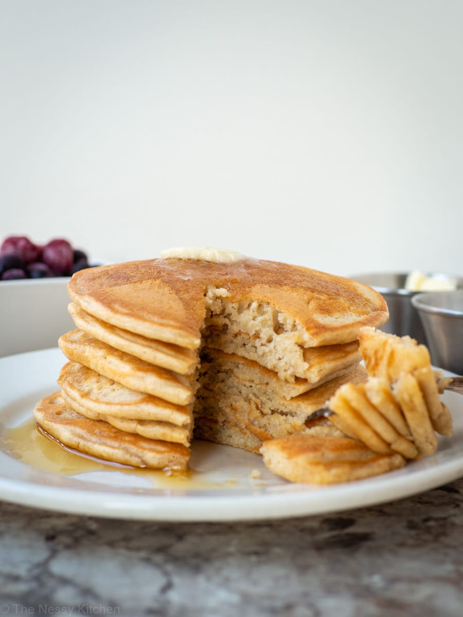 Stack of fluffy oat flour pancakes with a bite taken out.