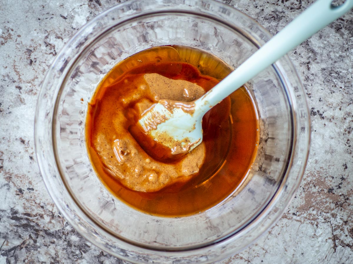 Maple syrup, almond butter and vanilla mixed together in a bowl.