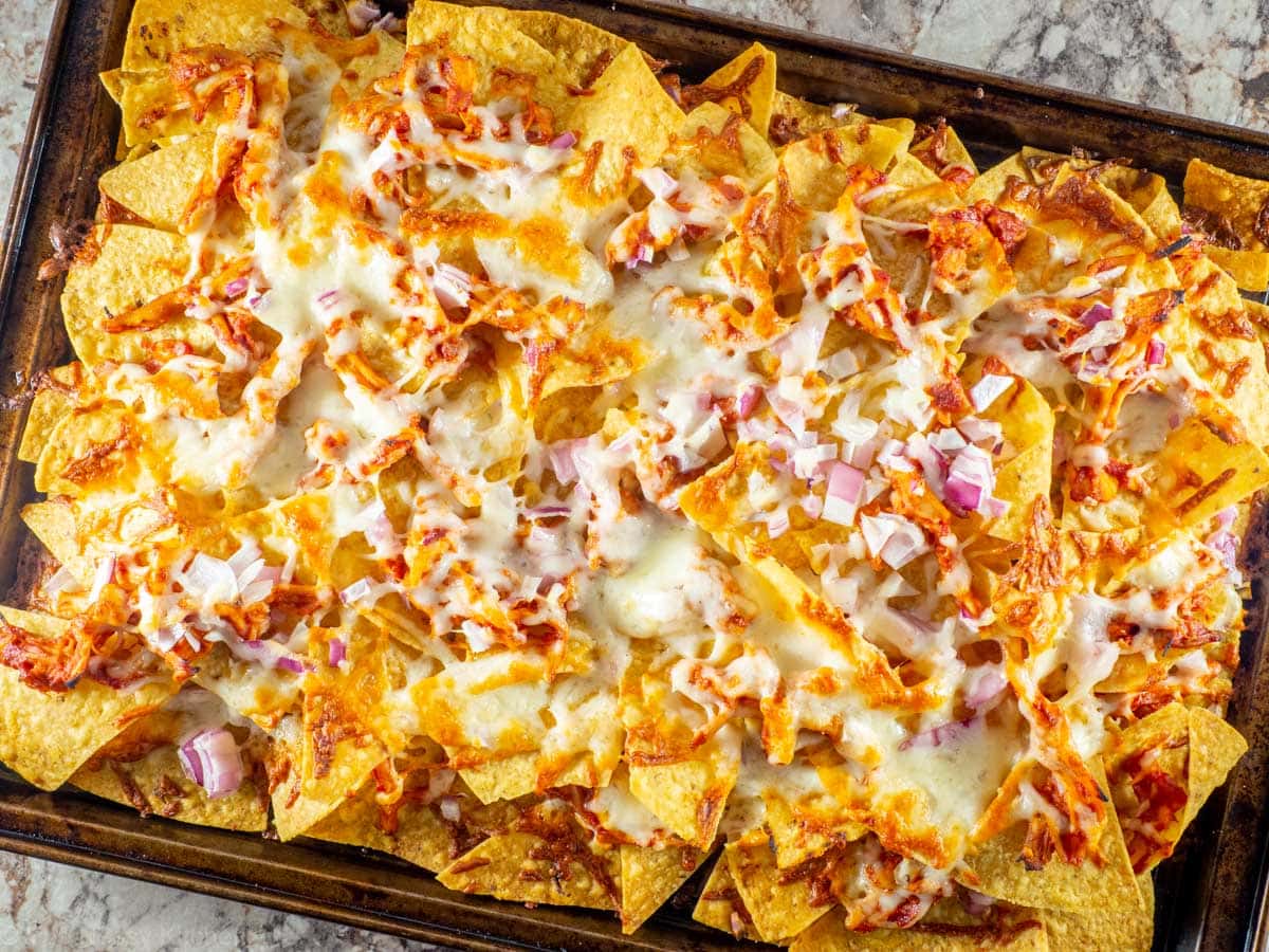 Baked nachos with melted cheese on a sheet pan.