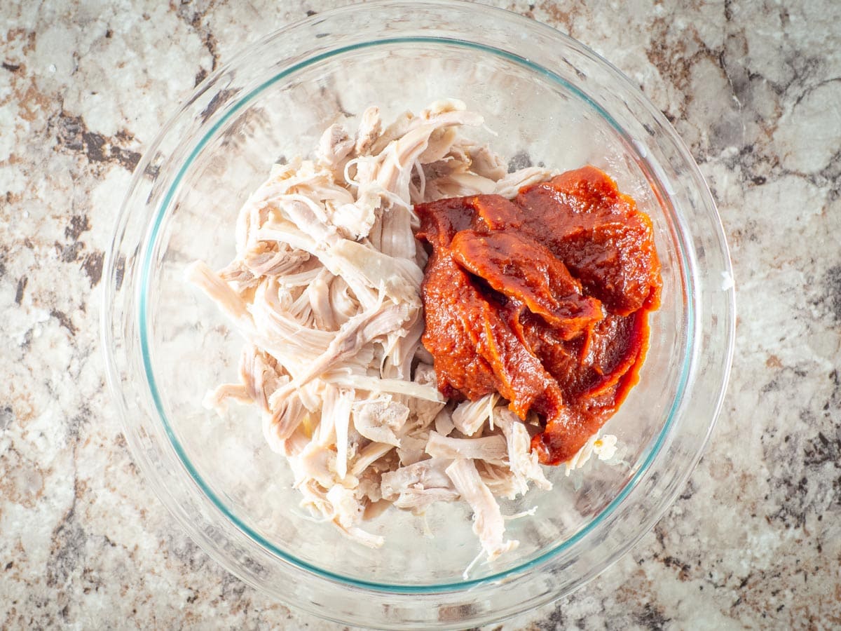 Shredded chicken and bbq sauce in a mixing bowl.