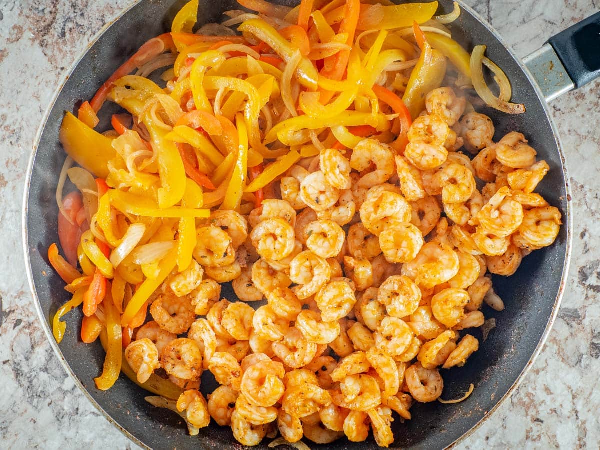 Shrimp and fajitas in a frying pan.