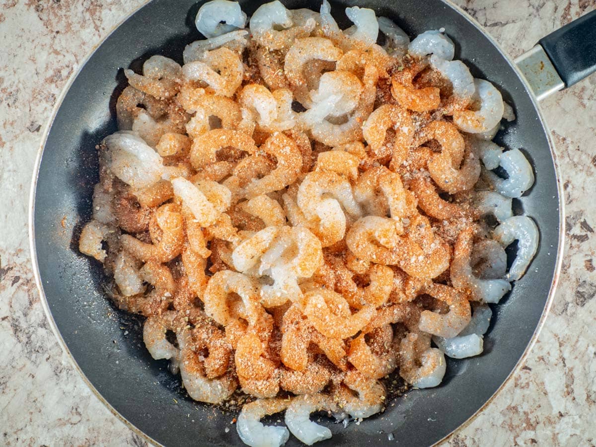 Shrimp in a frying pan topped with Cajun seasoning.