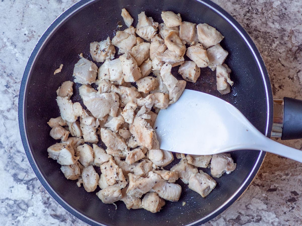 Diced chicken cooked in a skillet.