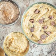 Three bowls of cookie dough hummus in different flavors including chocolate chip, peanut butter and snickerdoodle.