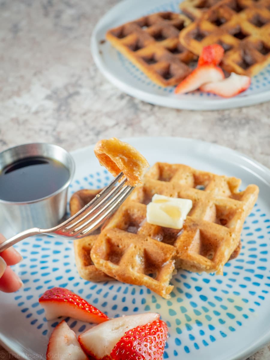 Fork holding up a bite of a waffle.