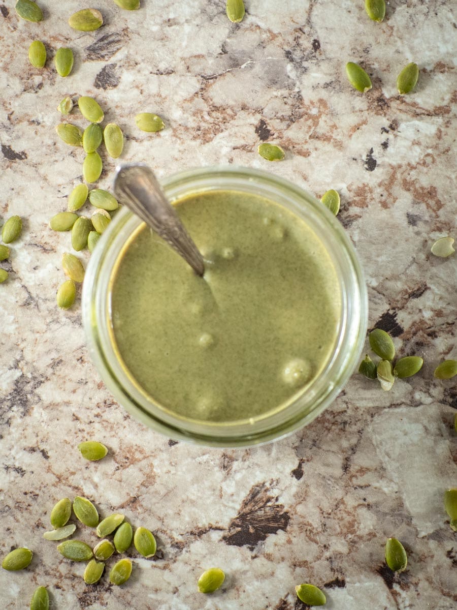 Top view of a jar of pumpkin seed butter with a spoon.