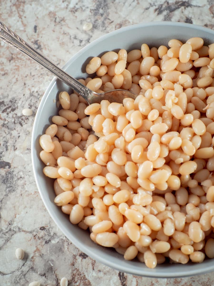 Cooked white beans in a grey bowl.