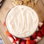 Bowl of vanilla hummus surrounded by strawberries.