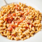Pasta with sautéed cherry tomatoes in a bowl.
