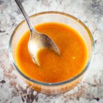 Red sauce in a bowl with a spoon.