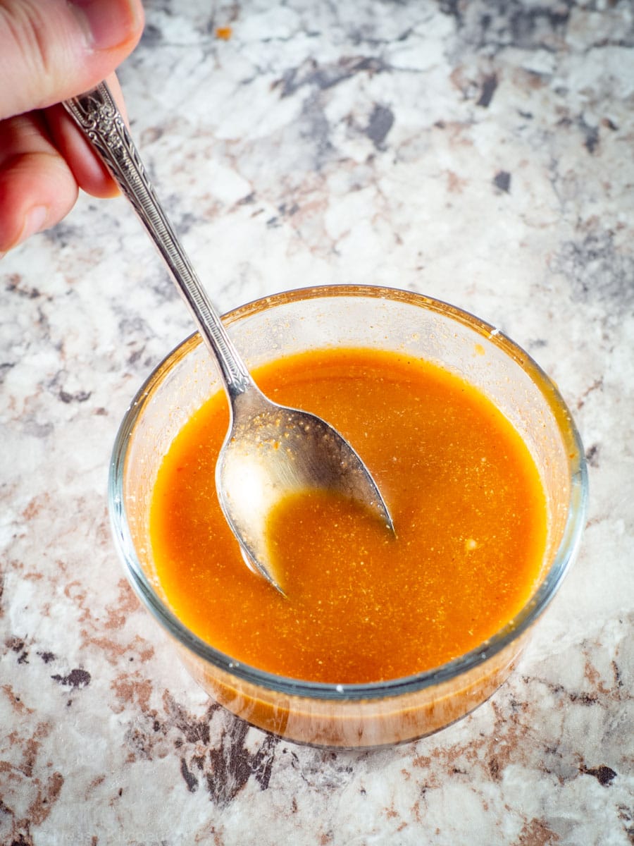 Spoon stirring sauce in a bowl.